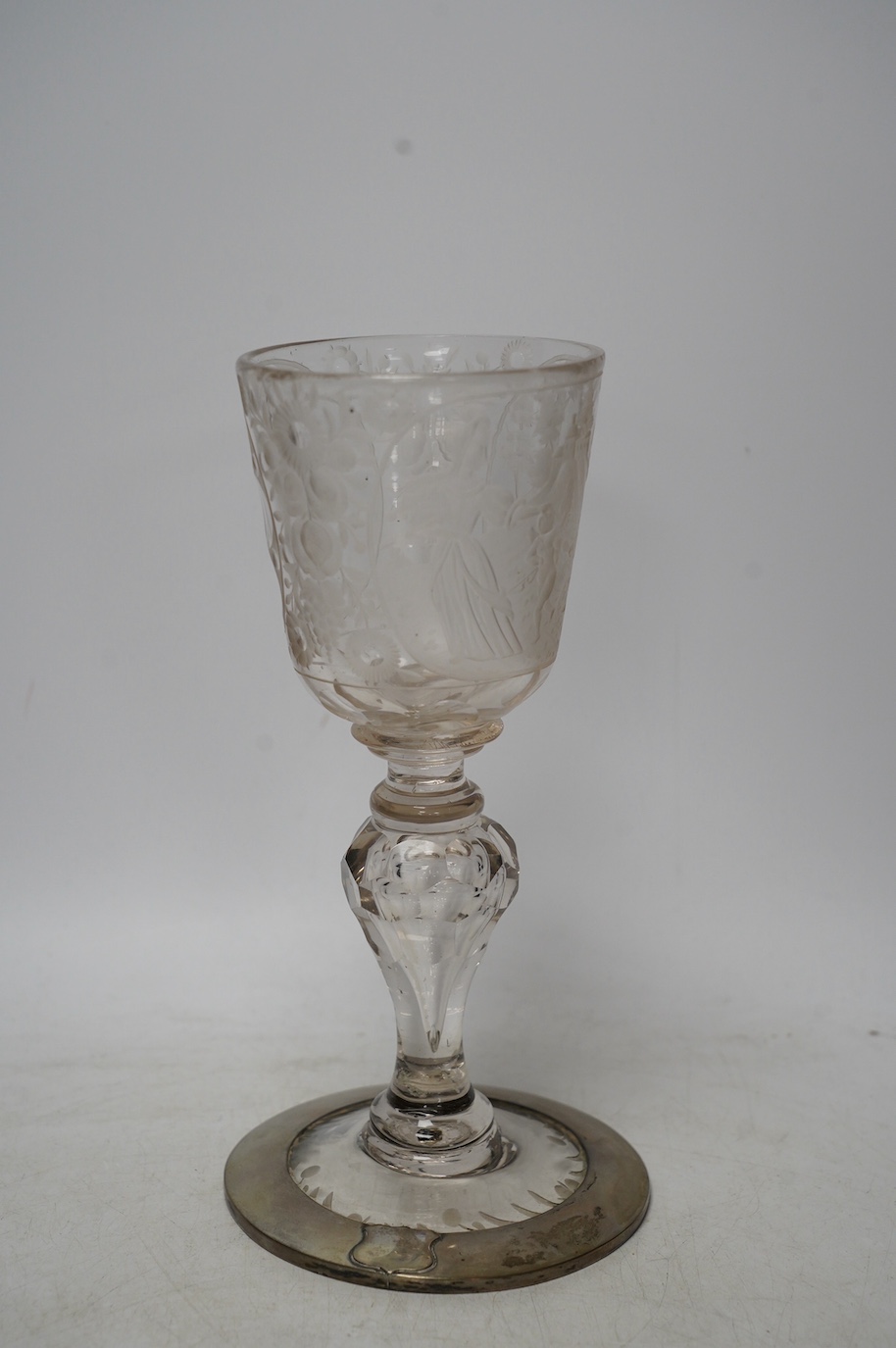 A Victorian engraved tall stemmed wine glass with white metal mounted foot rim, 22cm high. Condition - fair to good